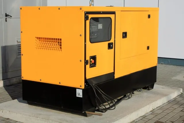 A yellow and black generator is parked in front of a building.