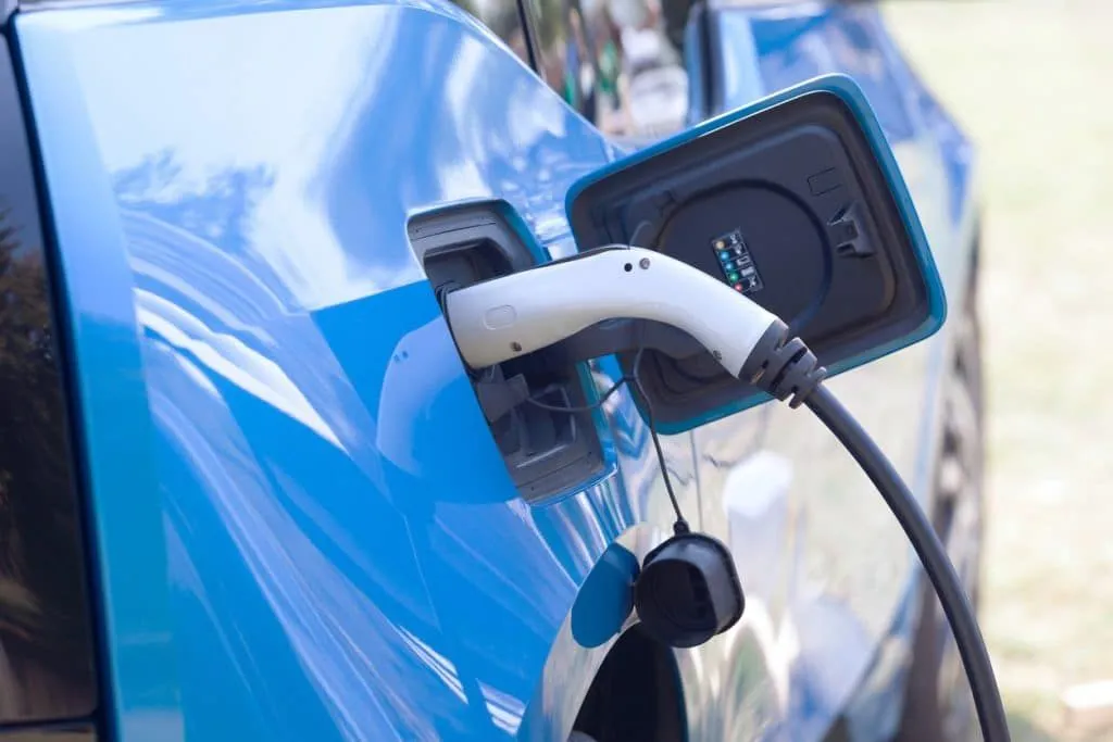 A blue electric car is being charged at a charging station.